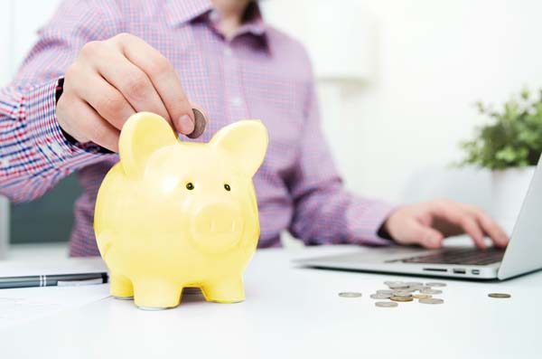 Geld wird in Sparschwein gesteckt